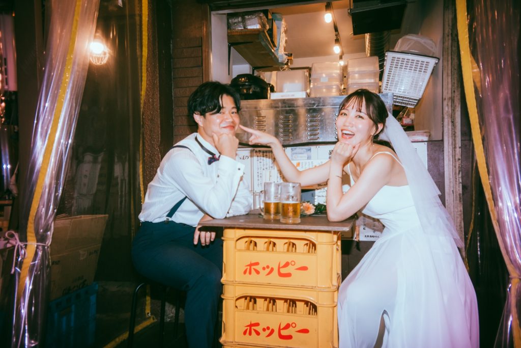 居酒屋の立ち飲みスペースで乾杯するドレス姿のふたり