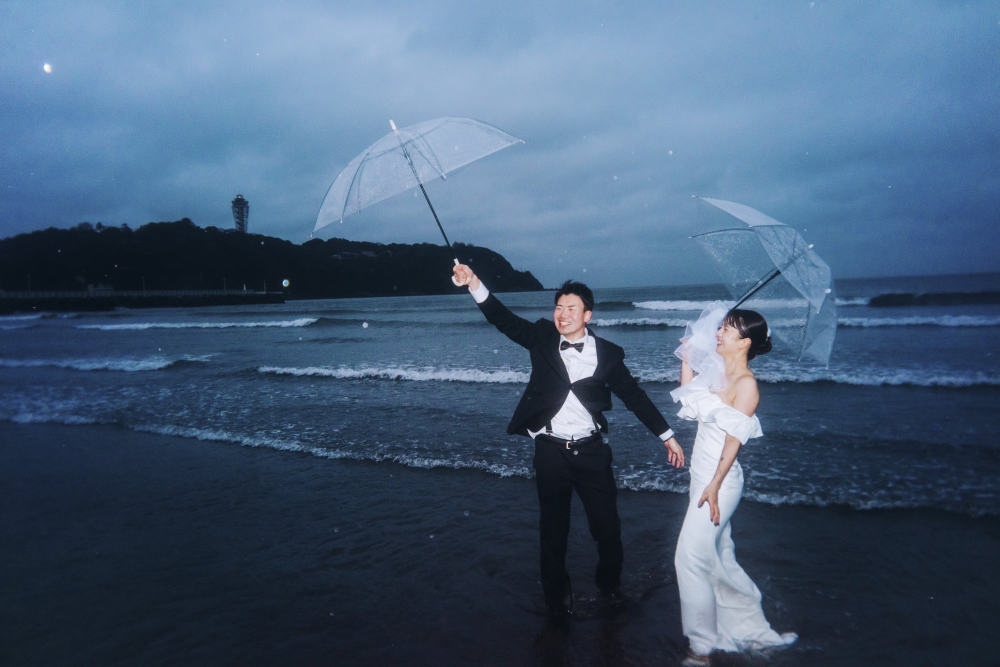 雨傘をさして七里ヶ浜を歩く前撮りカップル