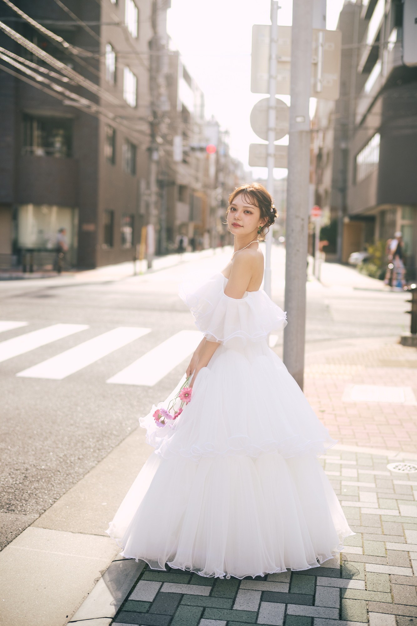 横断歩道を渡る軽いドレスの花嫁。街中前撮りの実例