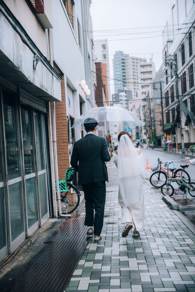 蔵前の雨の路地を透明傘をさして後ろ姿で歩くカップル写真