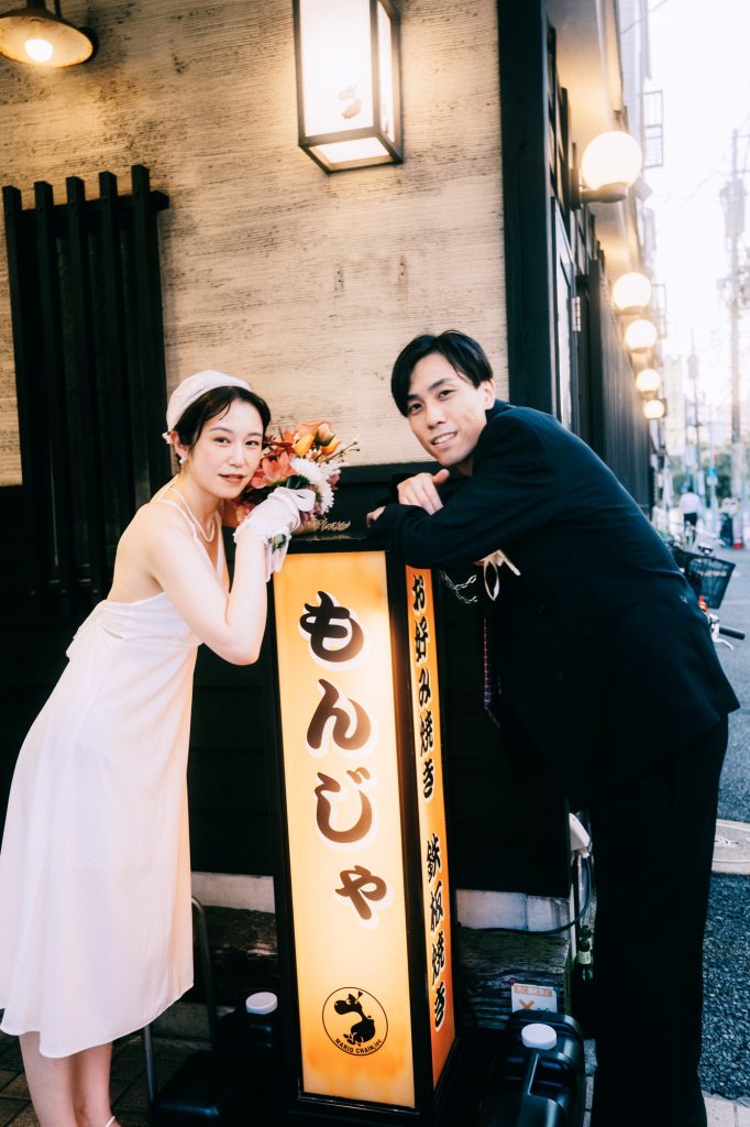 もんじゃ店の看板の前でポーズをとる新郎新婦｜月島もんじゃ通りの前撮り
