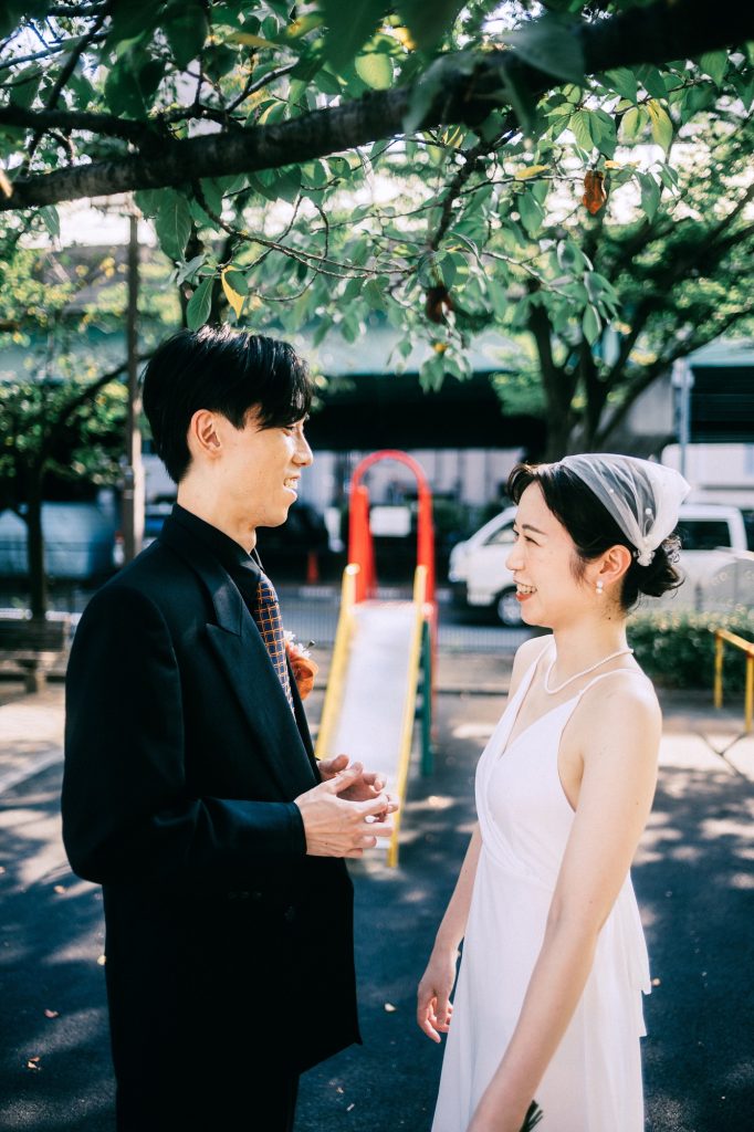 もんじゃ通りの緑の下で向かい合う新郎新婦|月島前撮り